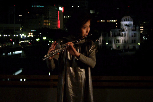 原爆ドームを背景にフルートを演奏する内田伽羅