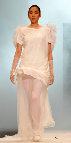 白鳥をイメージした衣裳でランウェイを歩くモデル