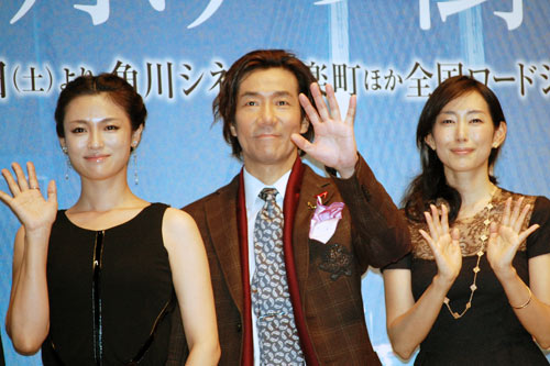 テレビカメラに手を振る3人。左から深田恭子、岸谷五朗、木村多江