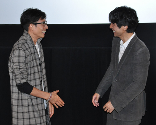握手をしてくださいとカメラマンに言われ、照れ笑いを浮かべる伊勢谷友介監督（左）と西島秀俊（右）