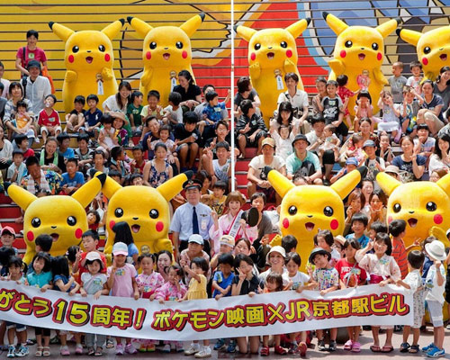 京都駅ビルの大階段に掲出された巨大ポケモンステップアートの前で、9体のピカチュウと中川翔子らが記念撮影