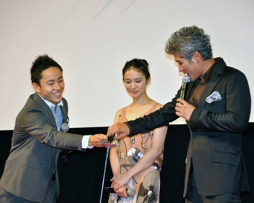 太田雄貴選手（左）にレクチャーされる吉川晃司（右）。中央は武井咲