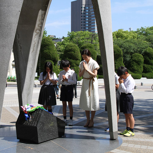 平和記念公園内にある原爆の子の前で子どもたちと一緒にお祈りする鈴木京香