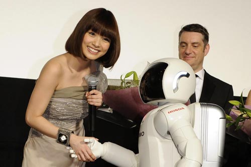 握手をする上戸彩（左）とASIMO（右）。右奥は監督のデビッド・バワーズ