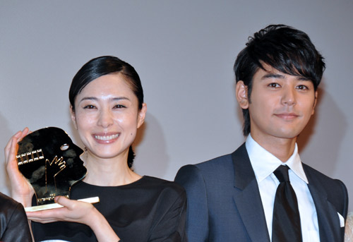 モントリオール世界映画祭最優秀女優賞のトロフィーを手にした深津絵里（左）と妻夫木聡（右）