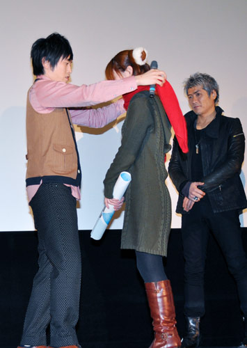 「村上純ワラライフ!!大賞」受賞者の女性（中央）に記念品のマフラーを巻いてあげる村上純（左）。右は吉川晃司