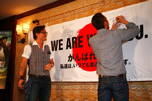 横断幕にメッセージを書き込む中田英寿（右）とジョニー・デップ（左）