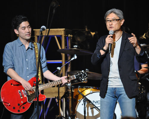 主題歌を歌う「THE RiCECOOKERS」と共にステージに上がる堤幸彦監督（右）