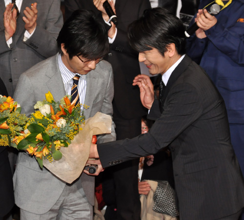 田中圭（左）に花束を渡す及川光博（右）